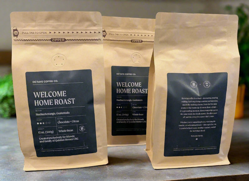 Three coffee bags from Octave Coffee Co. on a wooden surface with a blurred background.